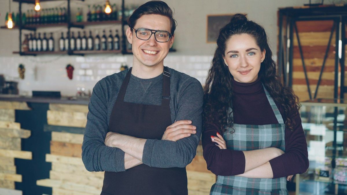 Two local business owners standing behind their counter
